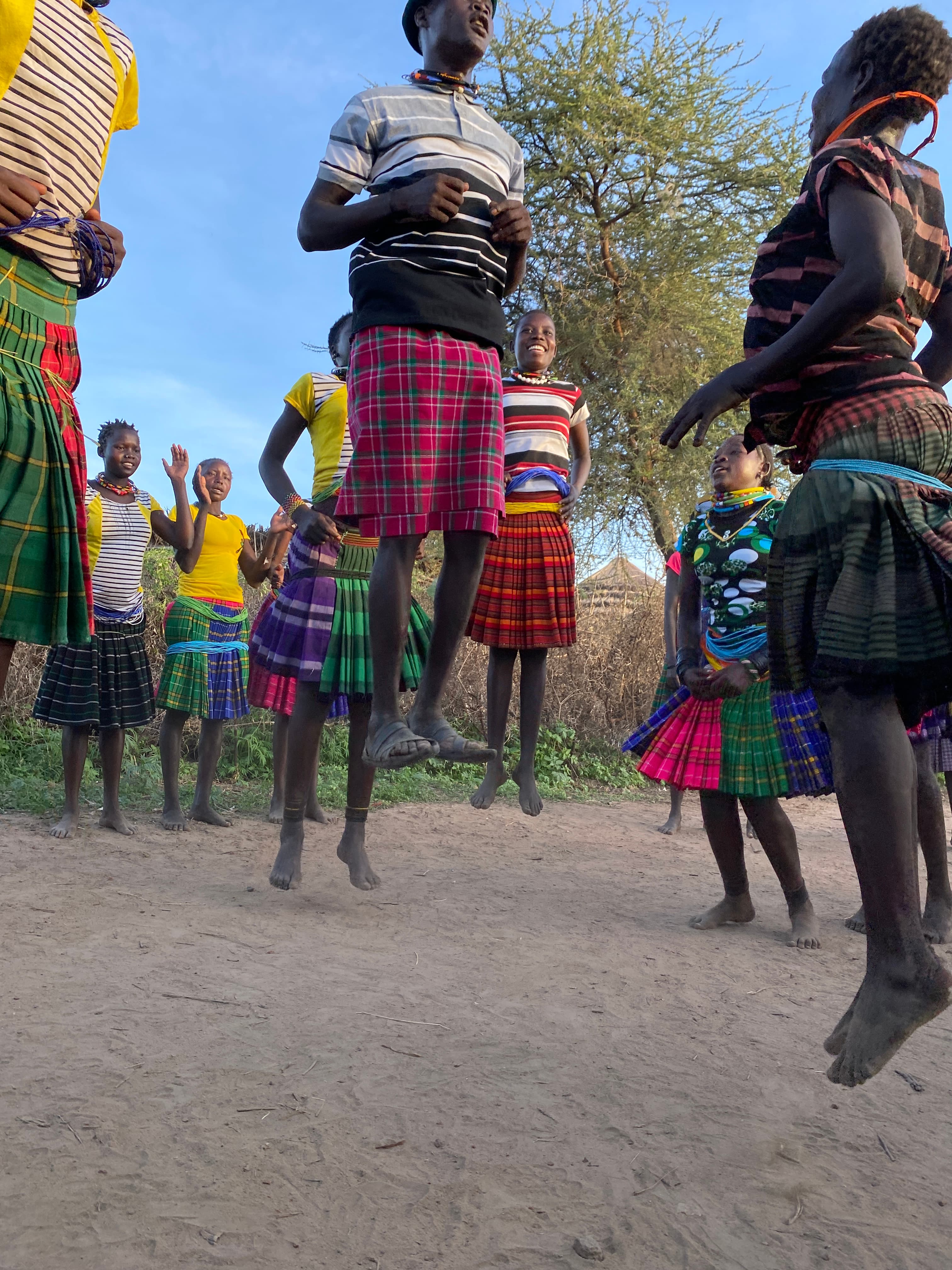 A Karamojong man thatching the conical roof of a traditional manyatta in Nadunget, Moroto Uganda, against a blue sky