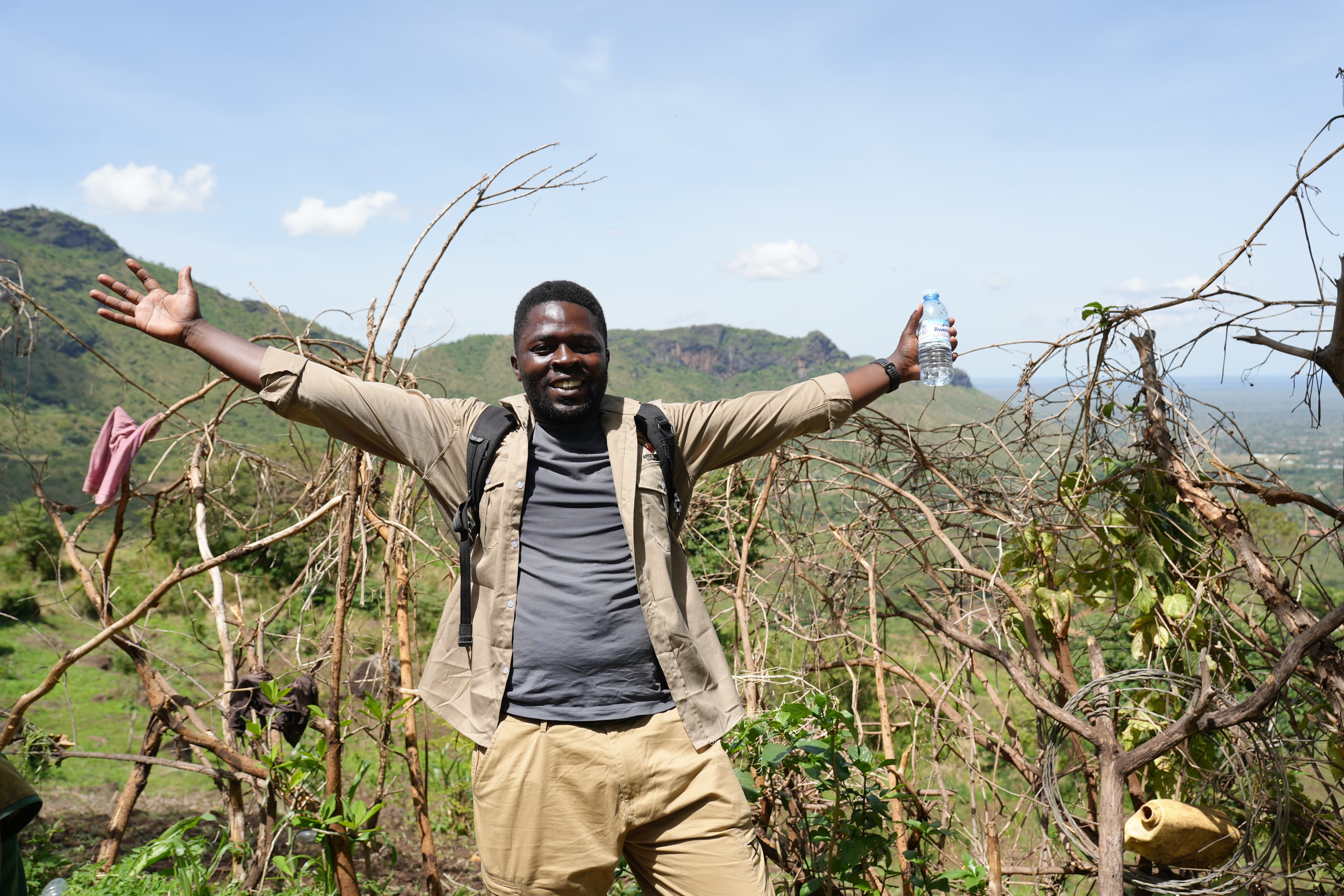 Two men standing at the red-earth foothills of Mt. Moroto, Karamoja Uganda, with the mountain behind them